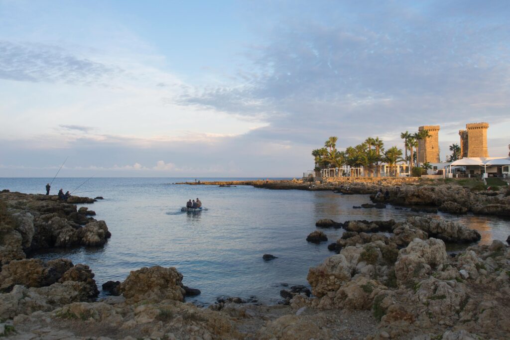 Beautiful coastal view in Santa Maria al Bagno, Puglia, with fishermen and historic buildings.